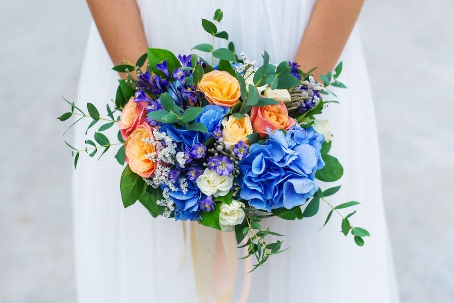 Bride-holding-blue-flower-bouquet-in-white-dress