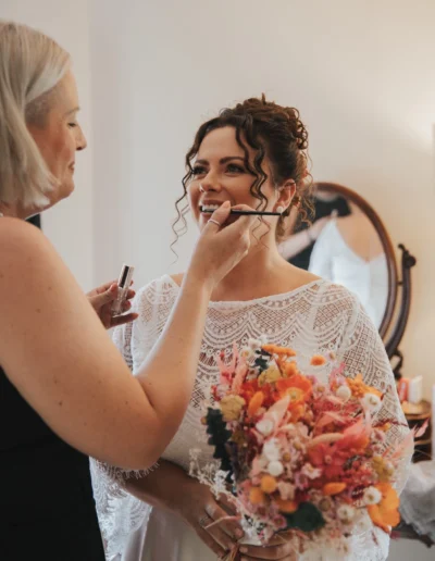Rachel Bray doing makeup on bride